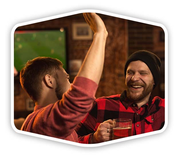 men-bar-whiteback Two men high fiving in a bar with football on the TV in the background