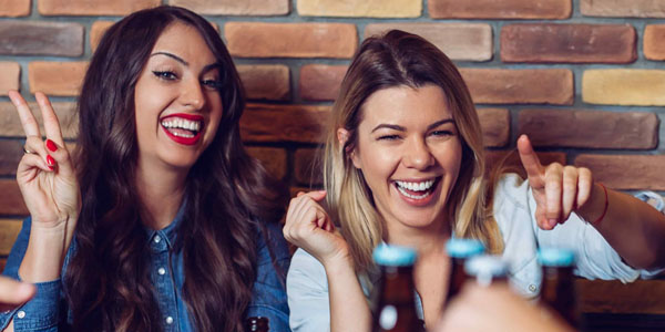 students Two women pointing and having fun in a bar
